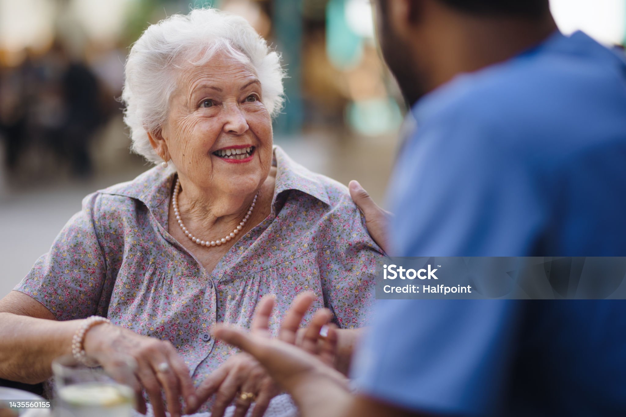 Caregiver talking with his client at a cafe, having nice time together. Pflegedienst Köln Herzblick